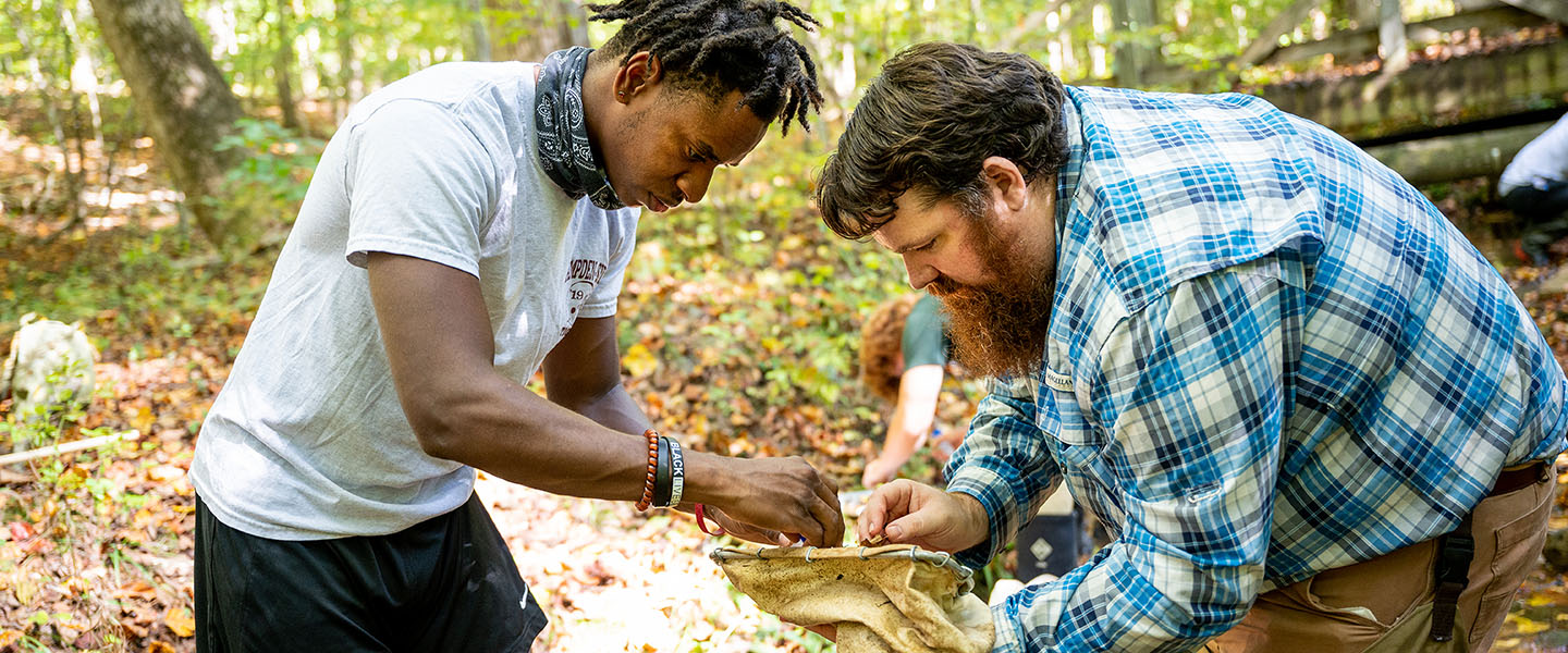 Professor with students looking in a creeknet