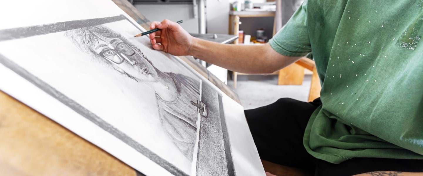 Student hand drawing a face on paper