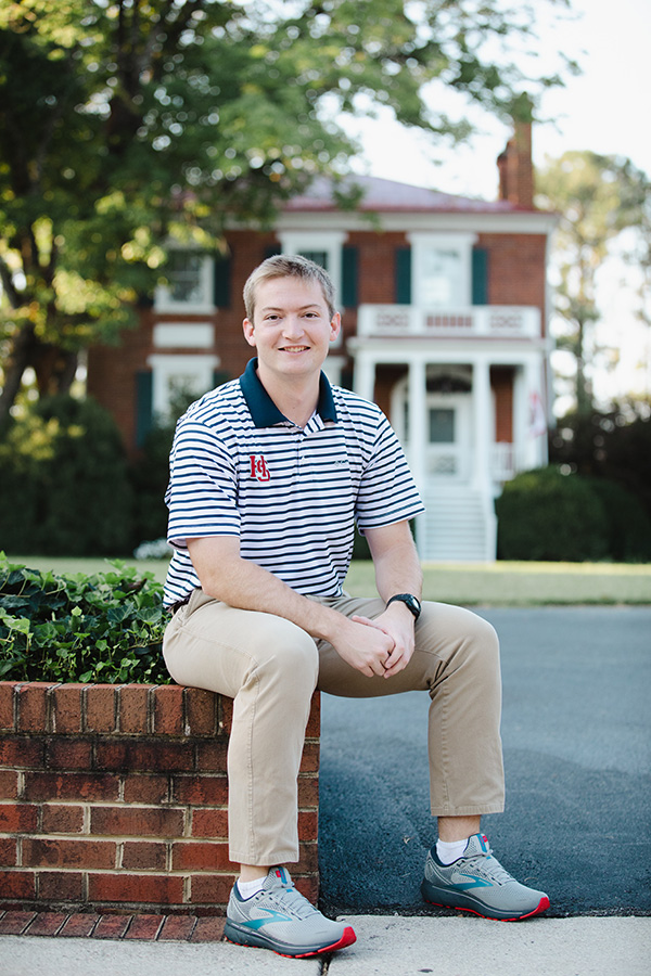 Michael Rowe'23 sitting in front of a campus building