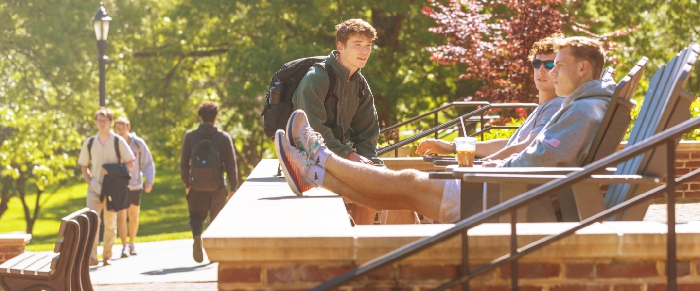 Students laughing and talking as they lounge on a terrace at Hampden-Sydney College.